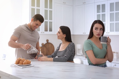 Unhappy woman feeling jealous while couple spending time together in kitchen