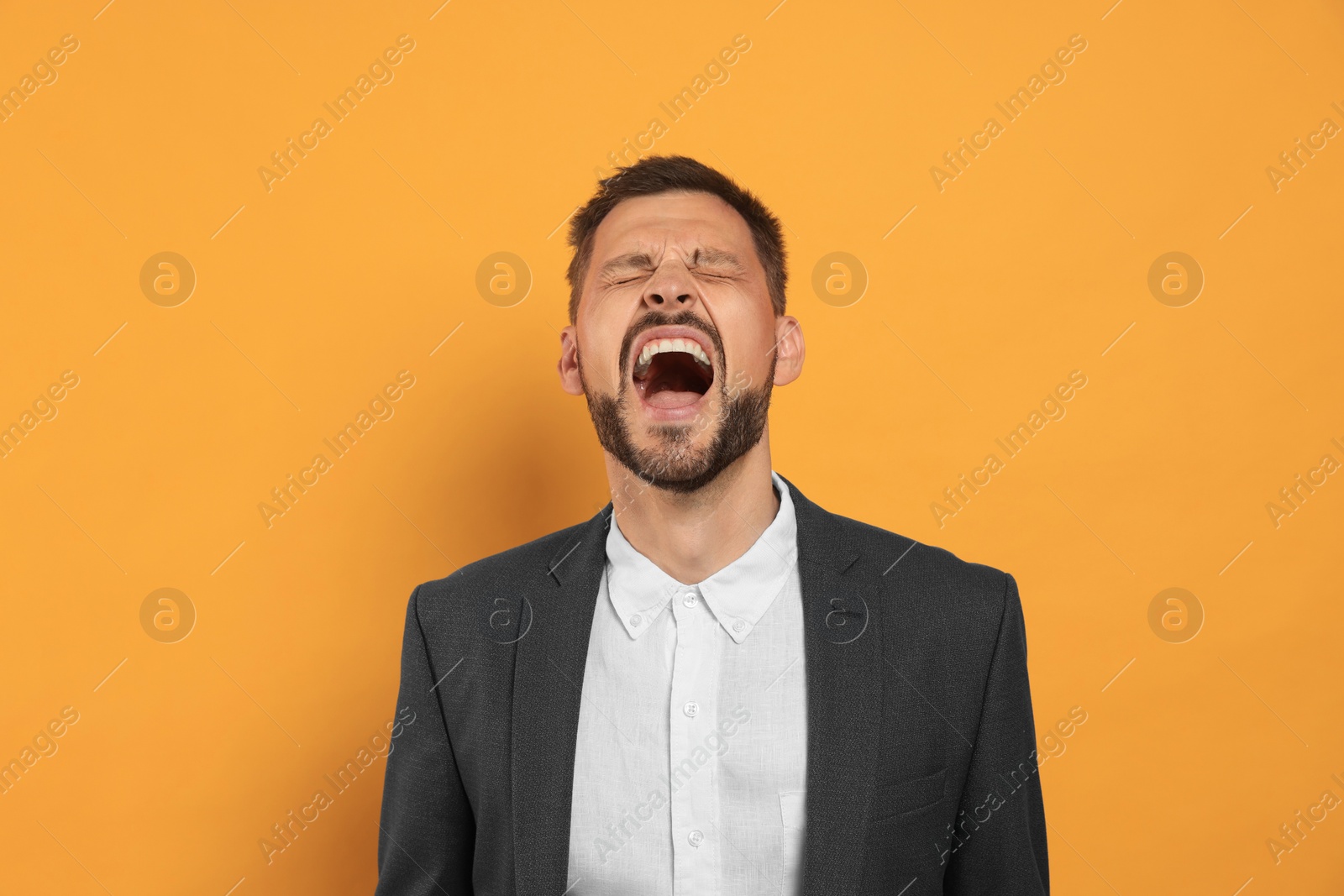 Photo of Aggressive man shouting on orange background. Hate concept