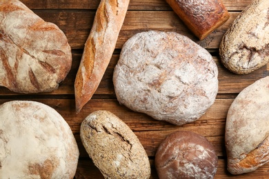 Different kinds of fresh bread on wooden table, flat lay