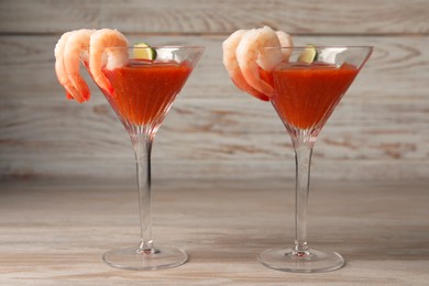 Tasty shrimp cocktail with sauce and lime in glasses on wooden table