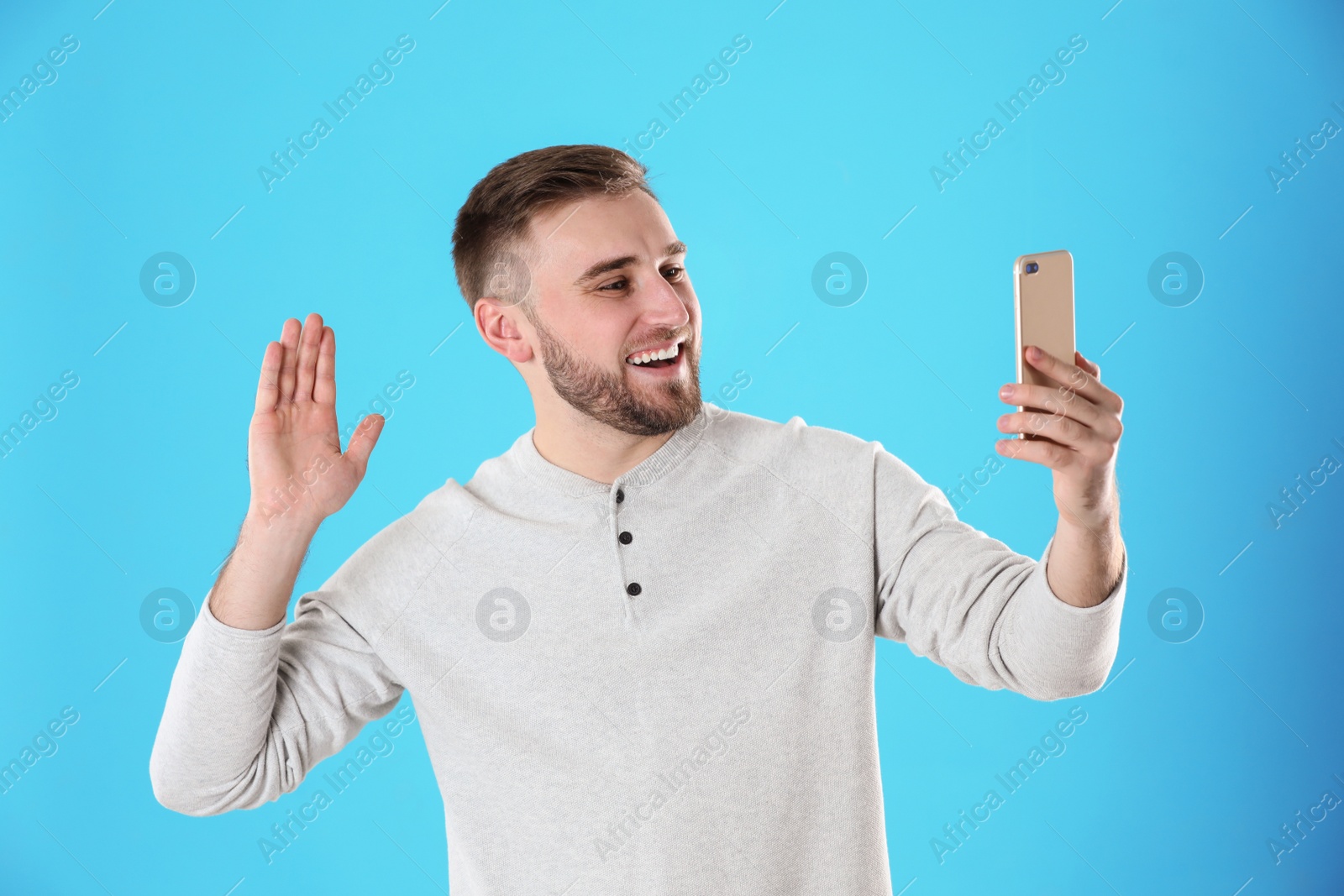 Photo of Young man using video chat on smartphone against color background