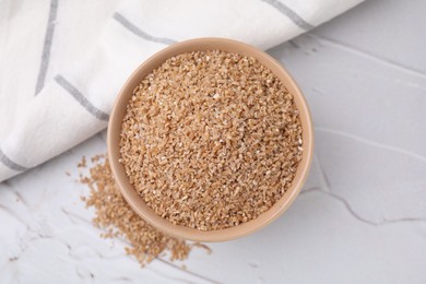 Photo of Dry wheat groats in bowl on light textured table, top view