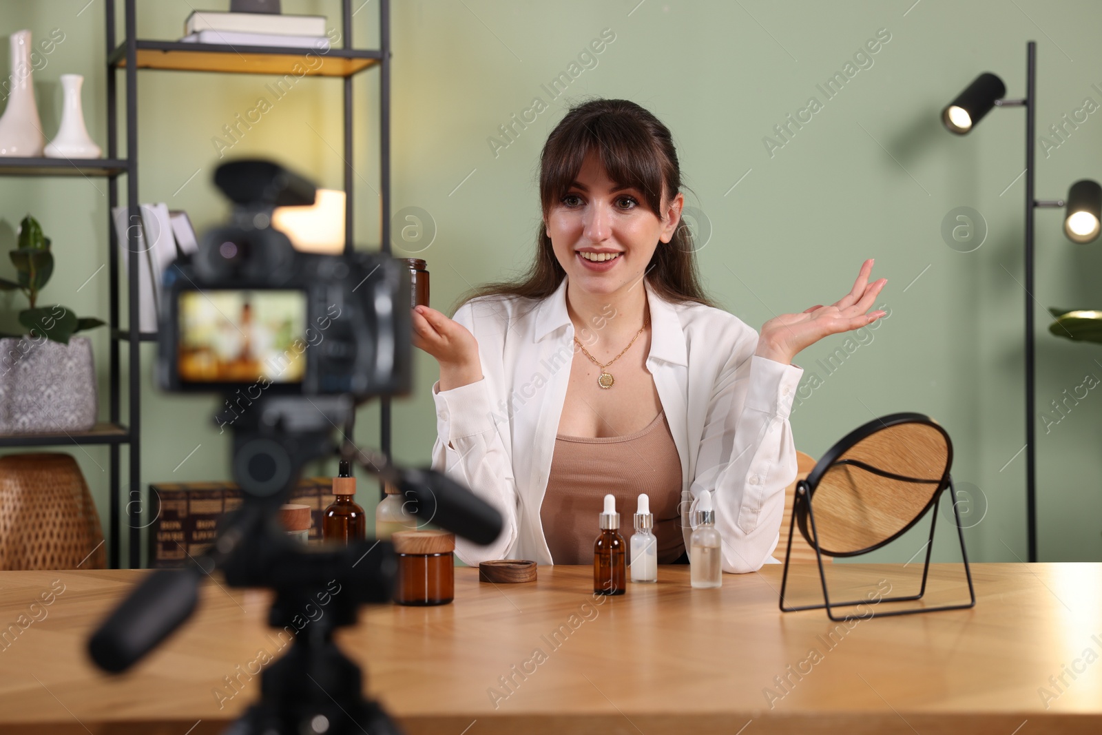 Photo of Smiling beauty blogger recording video while testing cosmetic products at home