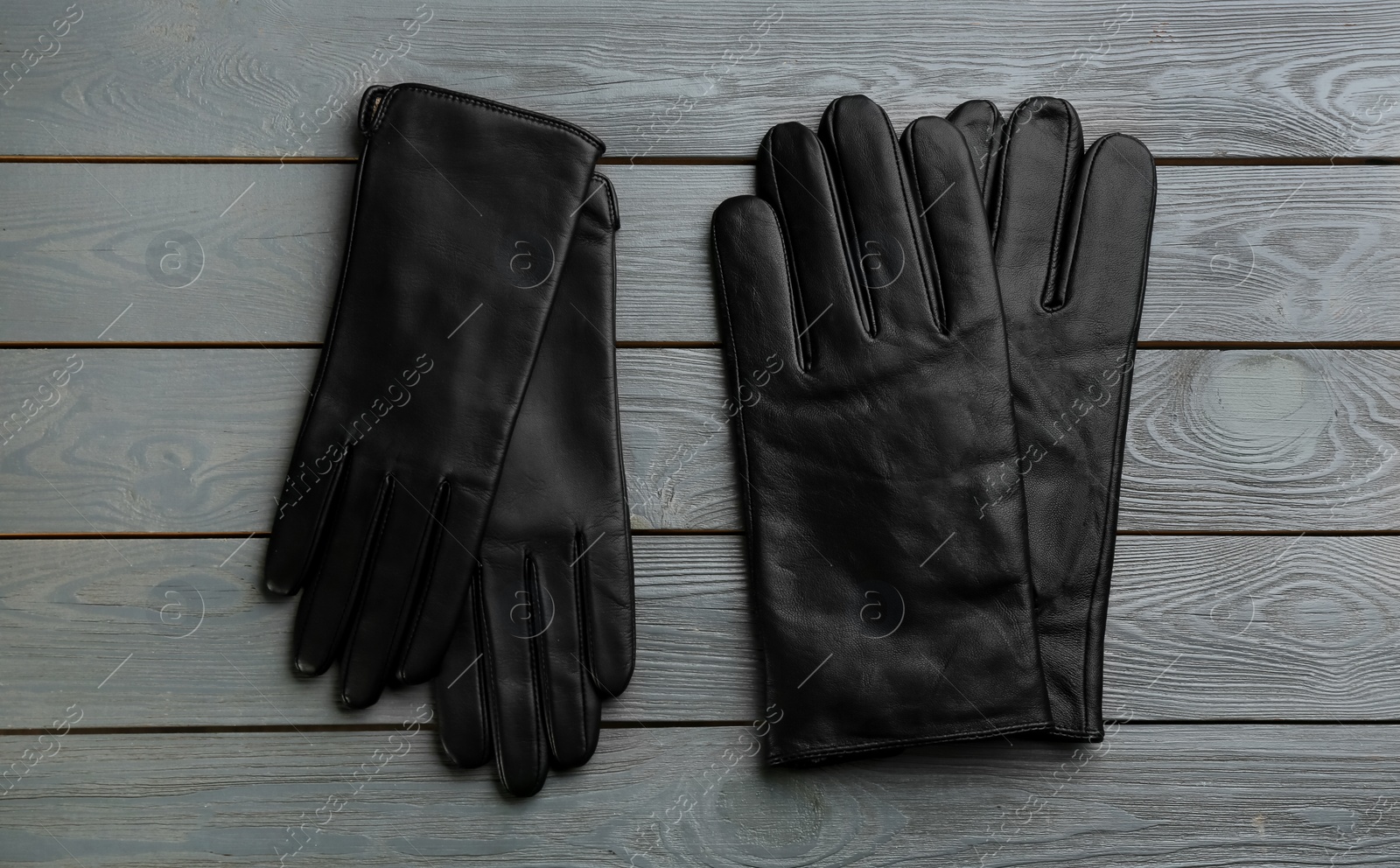 Photo of Stylish black leather gloves on grey wooden background, flat lay