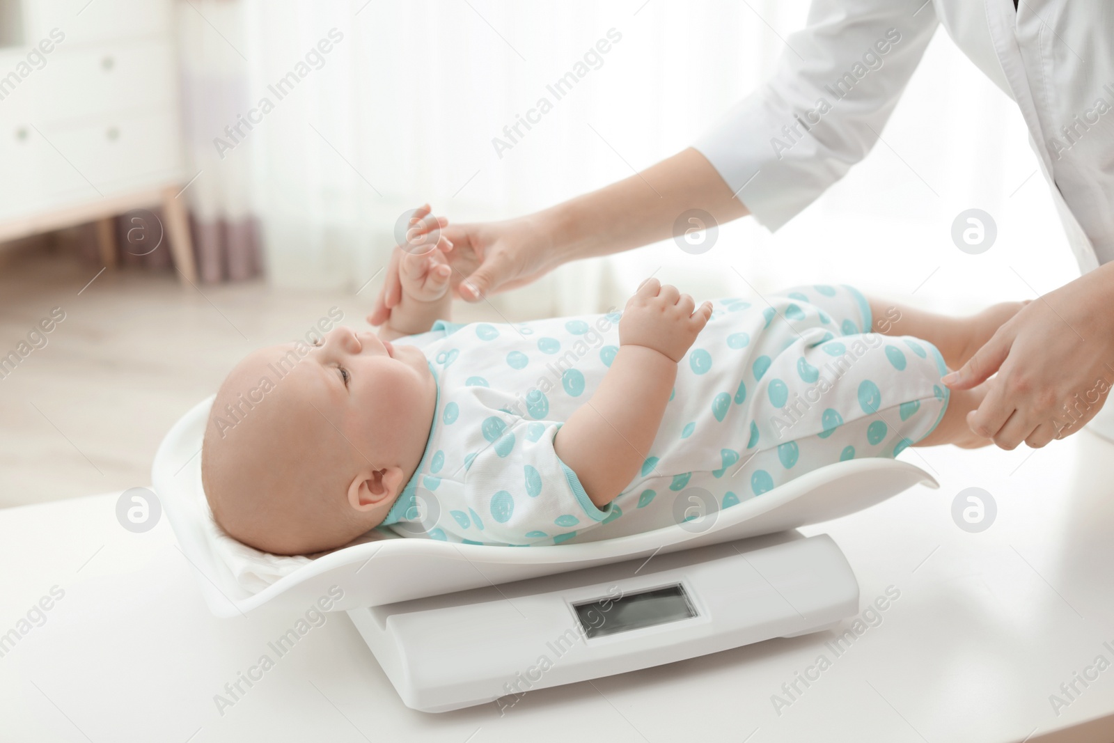 Photo of Doctor weighting baby on scales in light room