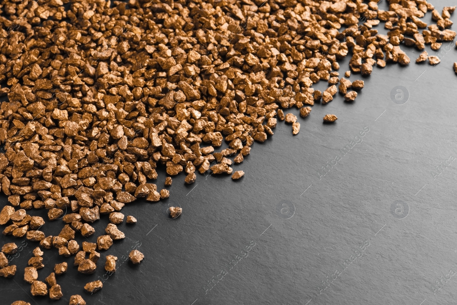 Photo of Pile of gold nuggets on black table. Space for text