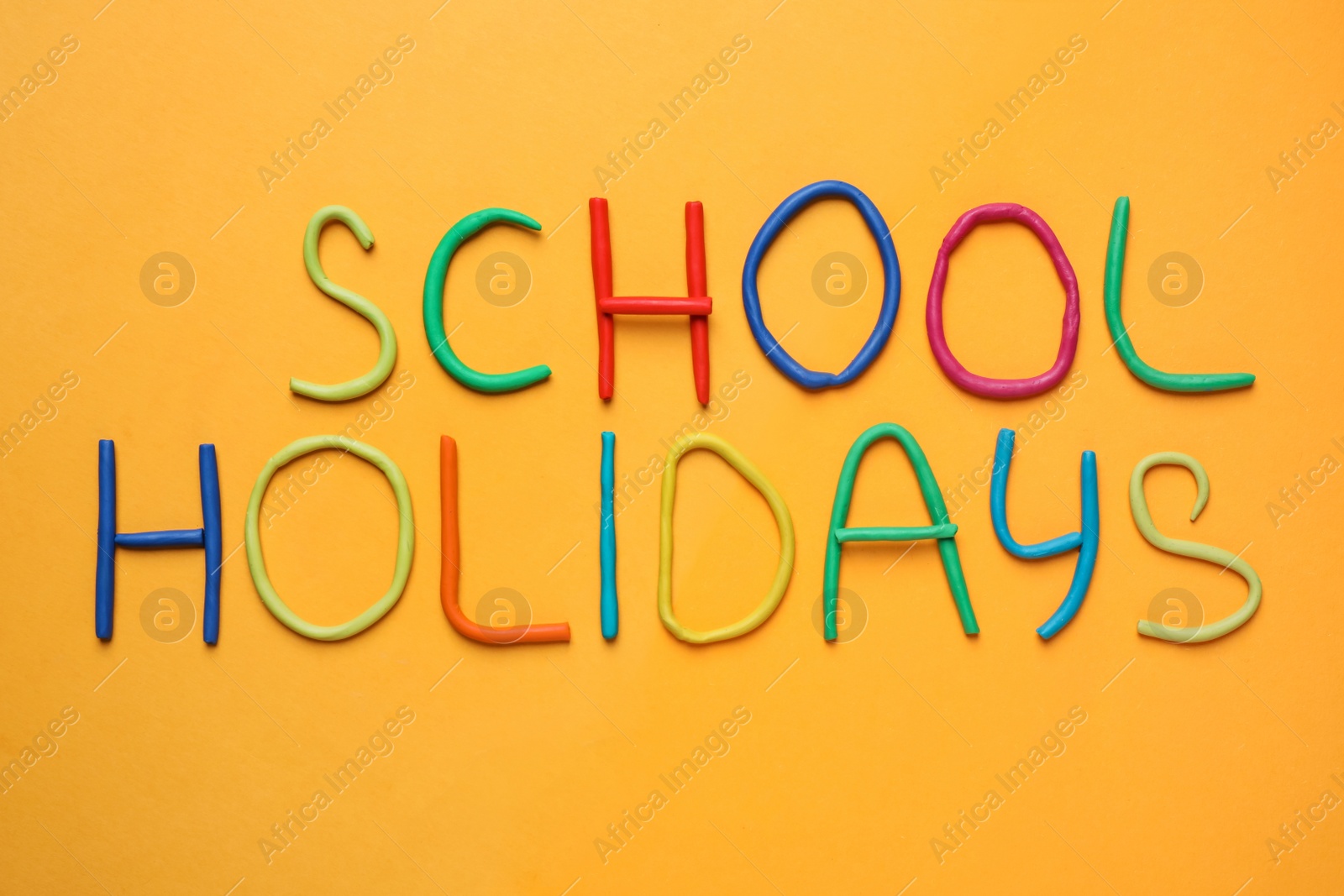 Photo of Text School Holidays made of modelling clay on orange background, flat lay