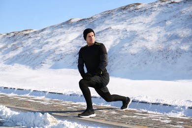 Photo of Man doing sports exercises outdoors on winter day