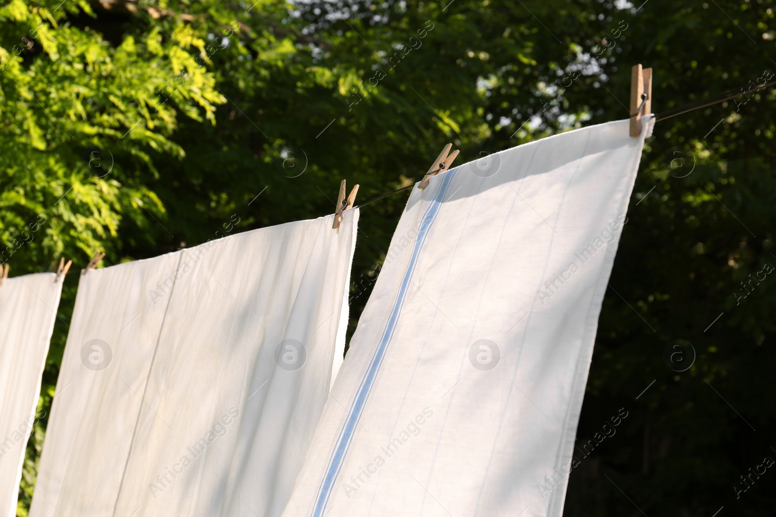 Photo of Washing line with clean laundry and clothespins outdoors