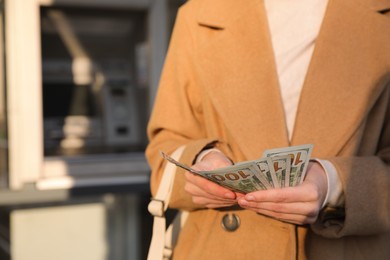 Photo of Woman with money near cash machine, closeup