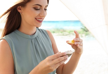 Woman squeezing lemon onto fresh oyster, outdoors