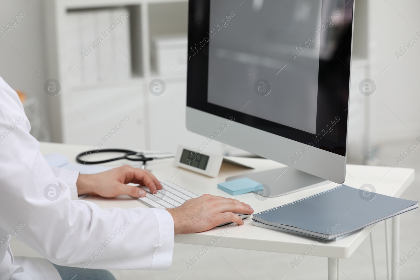 Photo of Doctor working with computer at desk in office, closeup