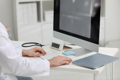 Doctor working with computer at desk in office, closeup