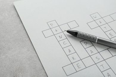 Photo of Crossword with answers and pen on old white table