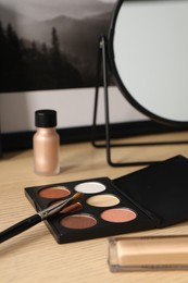 Photo of Mirror, makeup products and picture on wooden dressing table