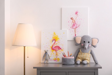 Photo of Chest of drawers and beautiful pictures in children's room. Interior design