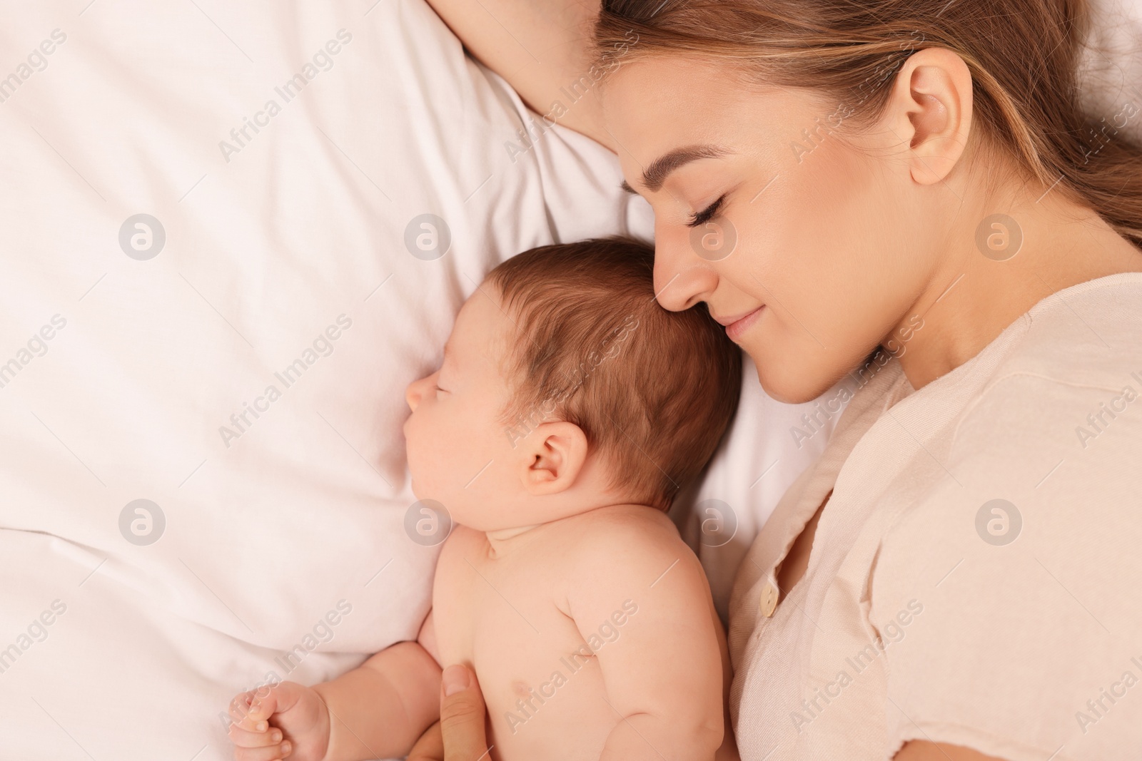 Photo of Mother and her cute newborn baby on bed, top view