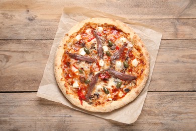 Tasty pizza with anchovies and olives on wooden table, top view