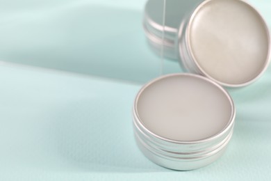 Photo of Lip balms on light blue background, space for text