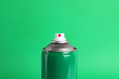 Colorful can of spray paint on green background, closeup