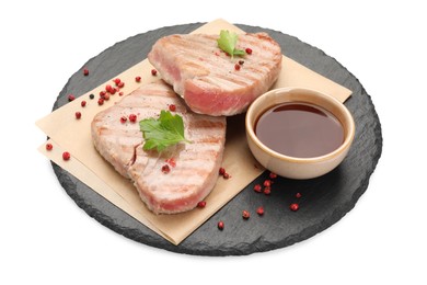 Photo of Delicious tuna steaks with sauce, parsley and spices on white background