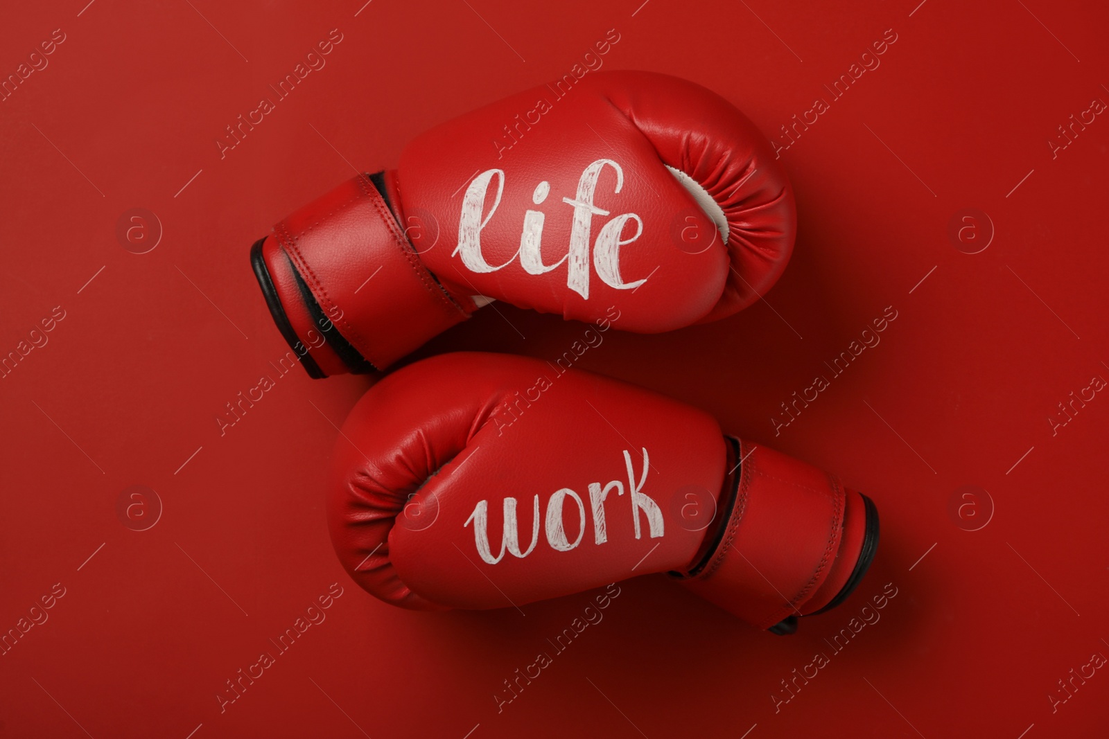 Photo of Boxing gloves with words Work and Life on red background, flat lay. Balance concept