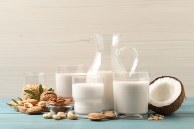 Photo of Different nut milks on light blue wooden table