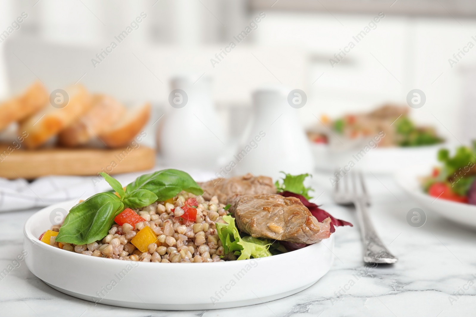 Photo of Tasty buckwheat porridge with meat on white marble table. Space for text