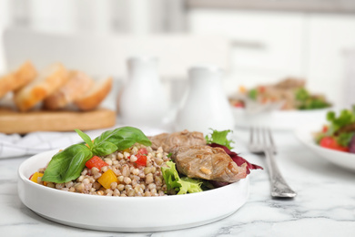 Photo of Tasty buckwheat porridge with meat on white marble table. Space for text