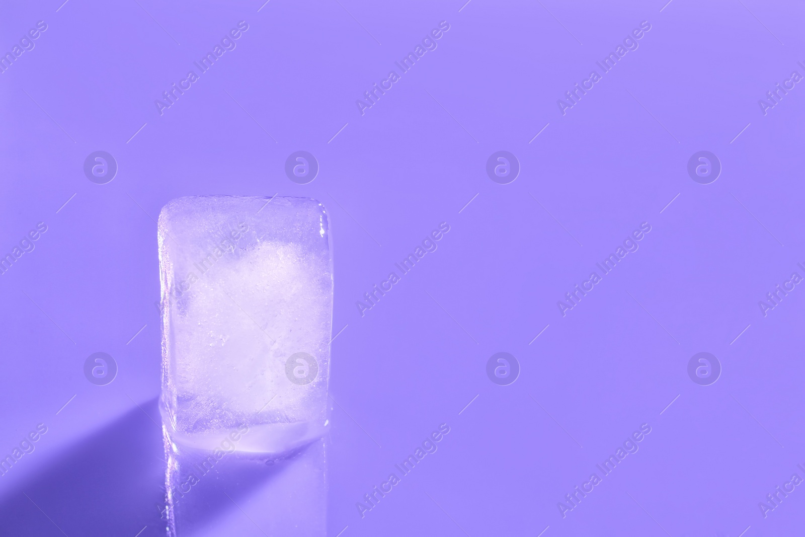 Photo of Ice cube on color background. Space for text