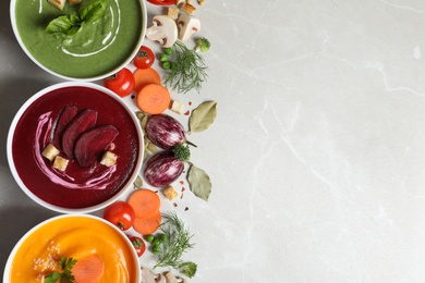 Photo of Various cream soups, ingredients and space for text on grey background, flat lay. Healthy food