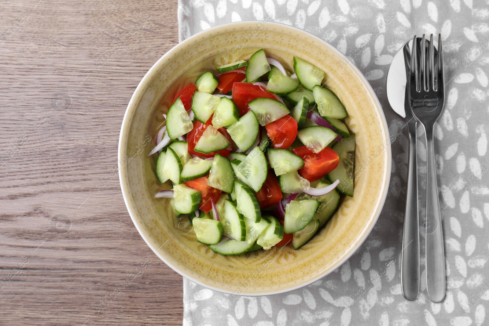 Photo of Bowl of vegetarian salad with cucumber, tomato and onion served on table, flat lay