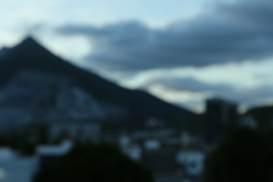 Photo of Blurred view of modern city and mountains at evening