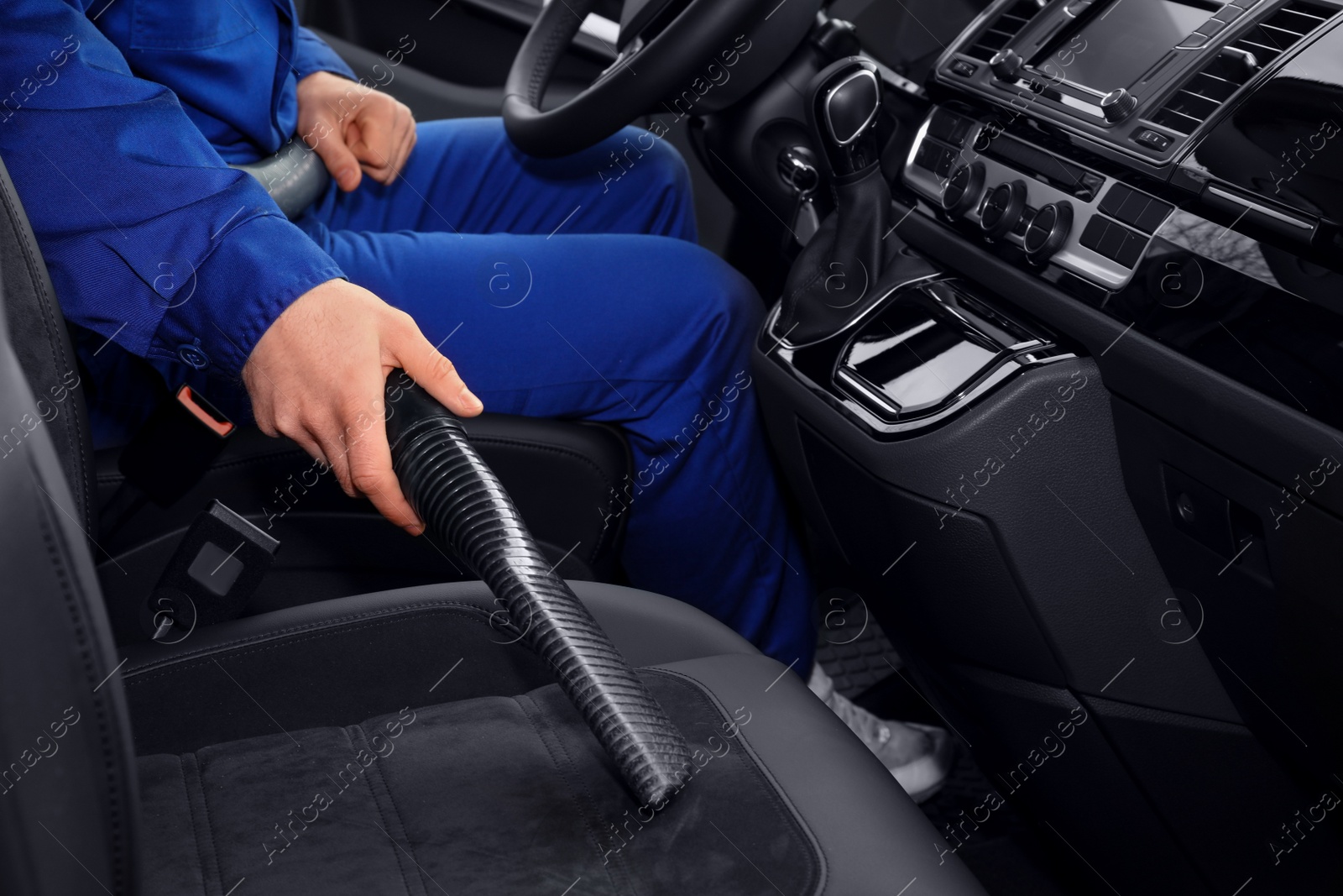 Photo of Car wash worker vacuuming automobile seat, closeup