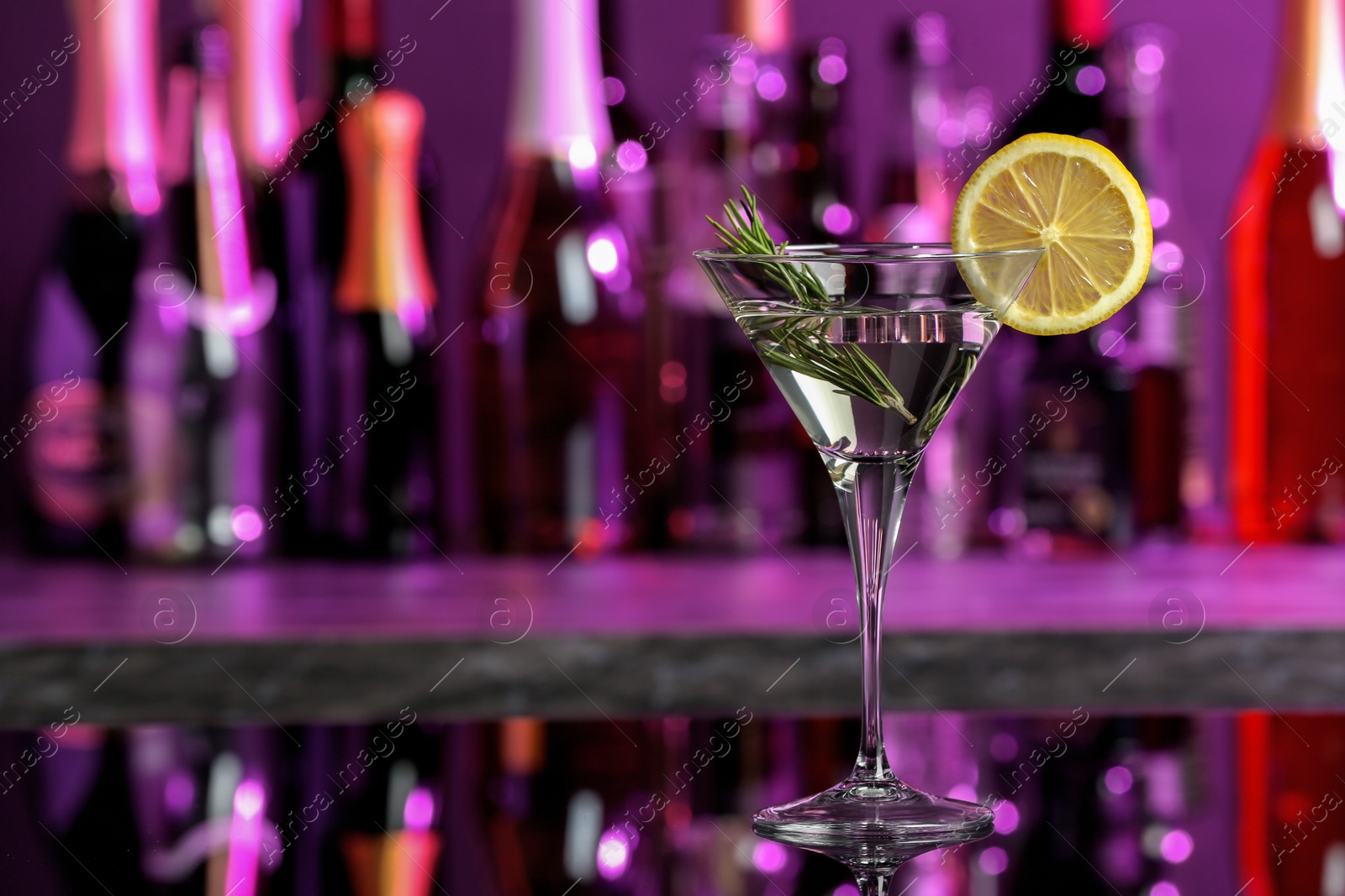 Photo of Martini glass of refreshing cocktail and lemon slice on mirror surface, space for text