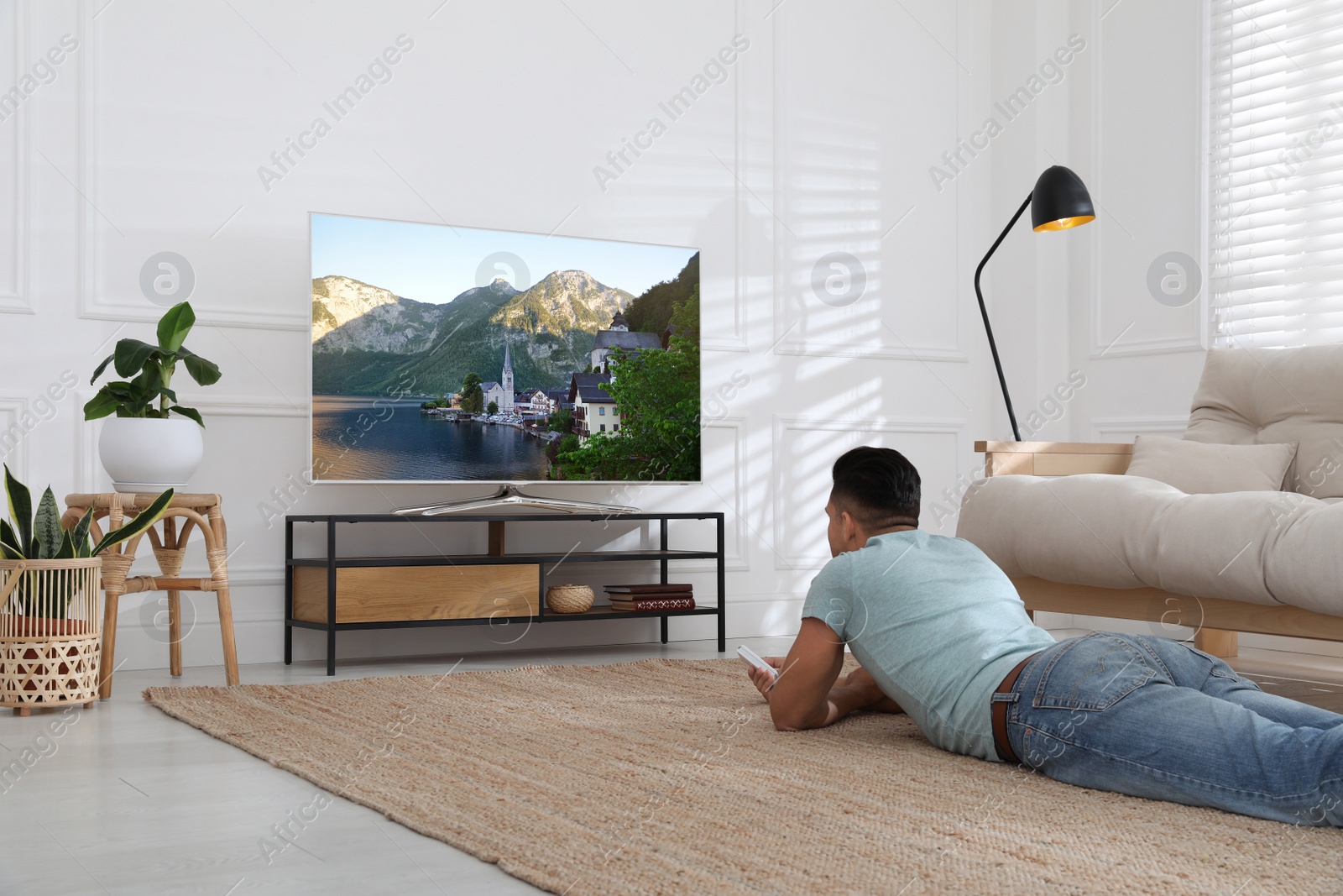 Photo of Man watching television at home. Living room interior with TV on stand