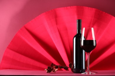 Photo of Stylish presentation of delicious red wine in bottle and glass on color background. Space for text