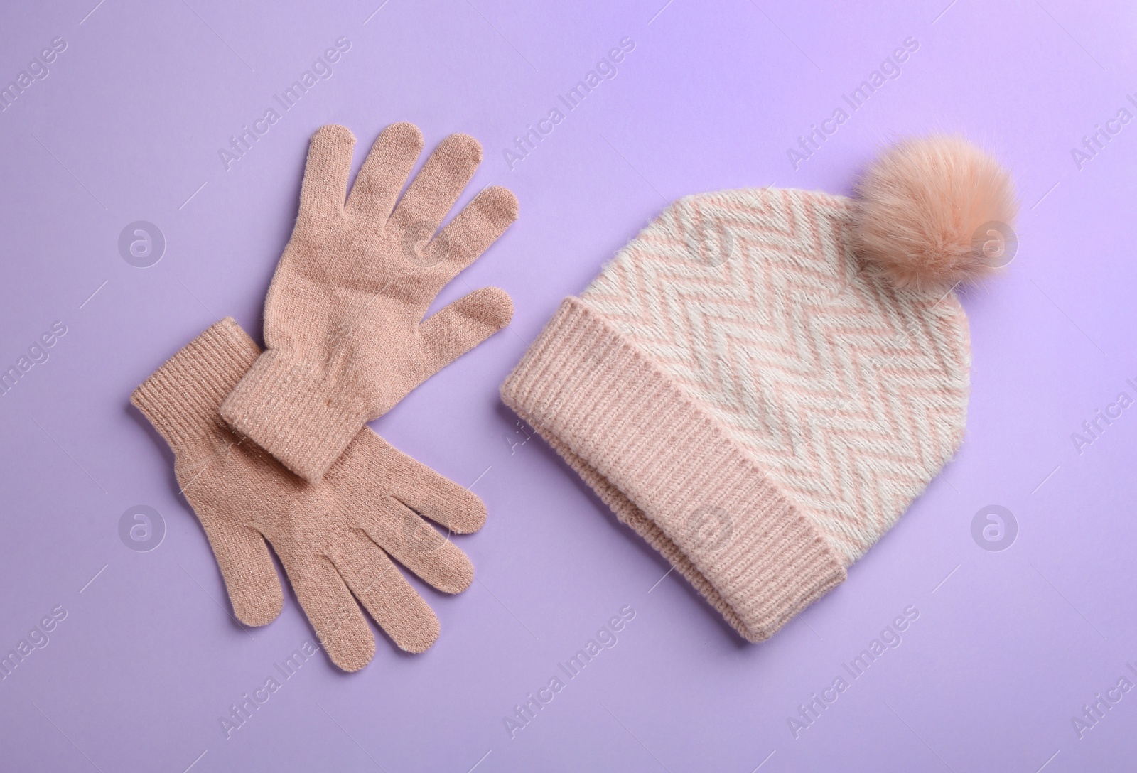 Photo of Woolen gloves and hat on violet background, flat lay