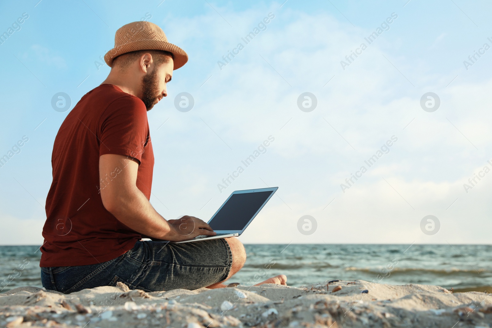 Photo of Man working with laptop on beach. Space for text