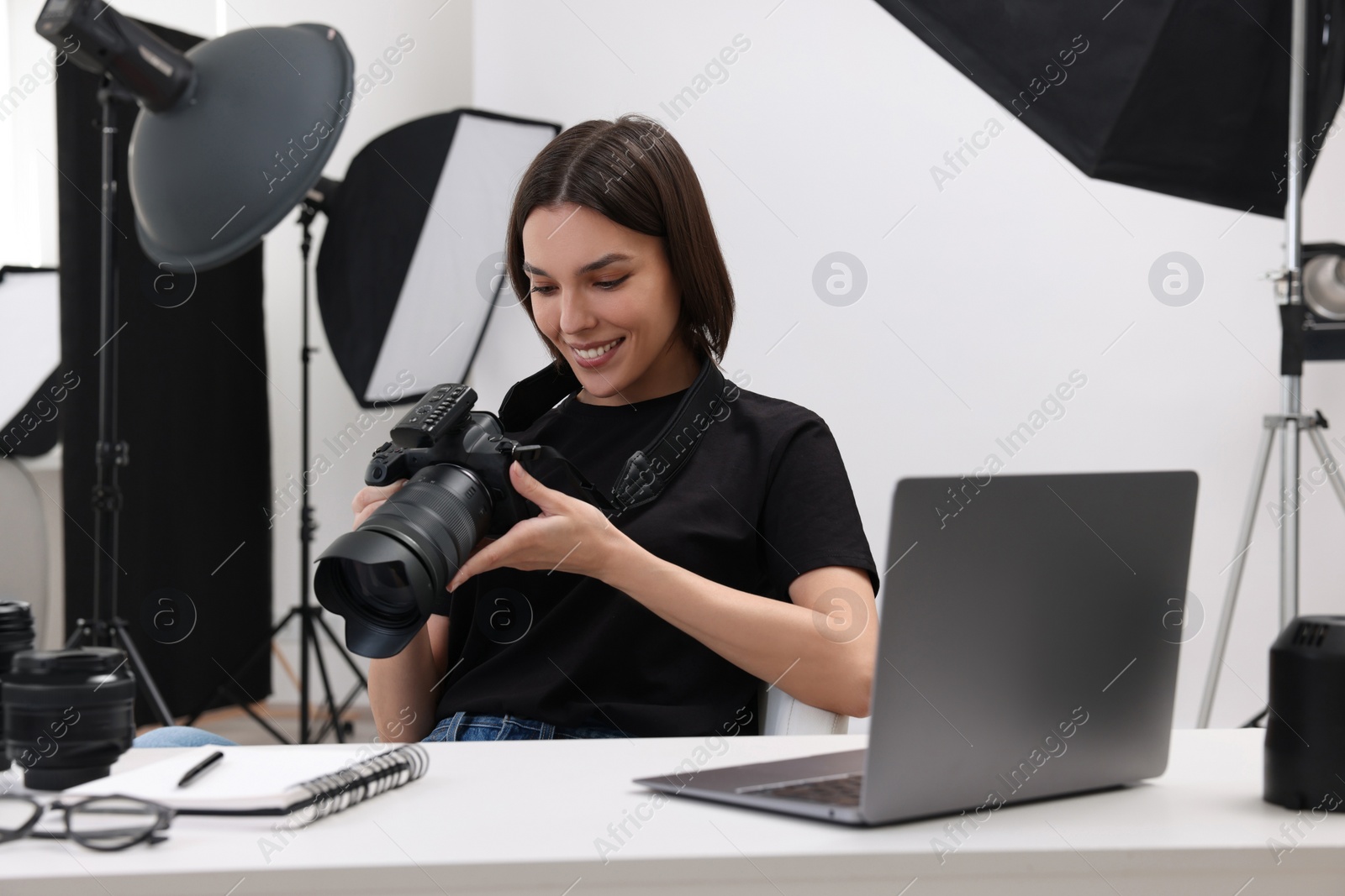 Photo of Young professional photographer with camera at table in modern photo studio