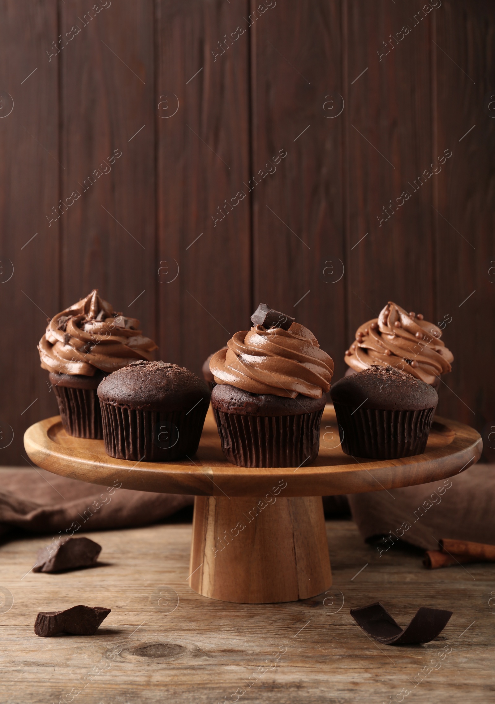 Photo of Delicious chocolate muffins and cupcakes decorated with cream on wooden table