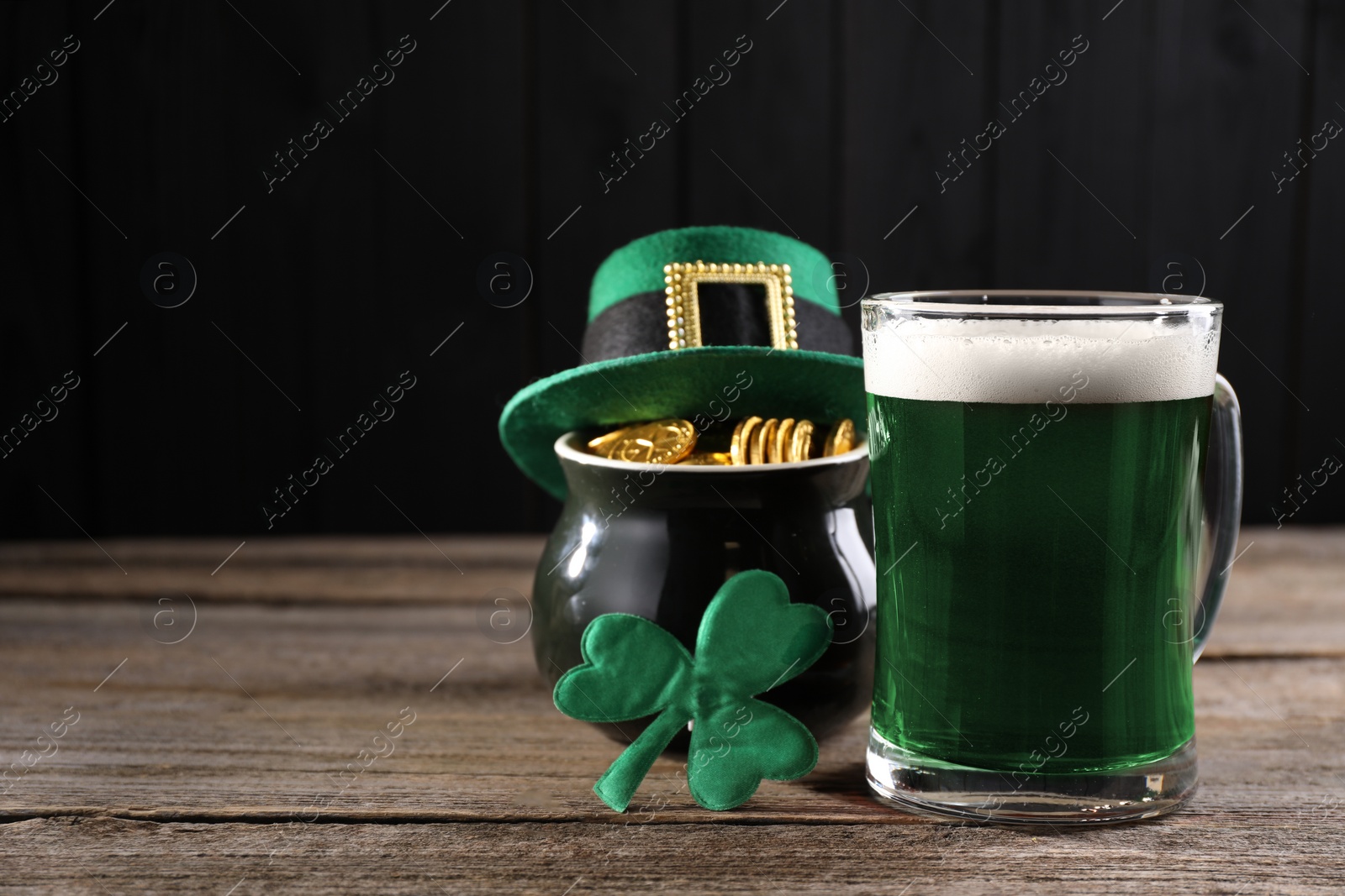 Photo of St. Patrick's day celebration. Green beer, leprechaun hat, pot of gold and decorative clover leaf on wooden table. Space for text