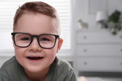 Photo of Cute little boy in glasses at home. Space for text