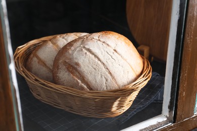 Fresh homemade bread in wicker basket, view through window