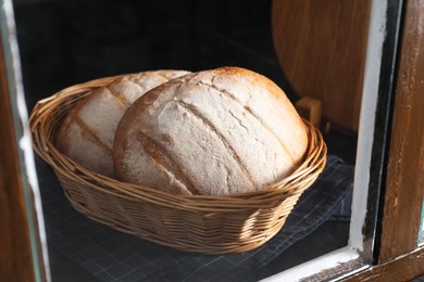 Photo of Fresh homemade bread in wicker basket, view through window