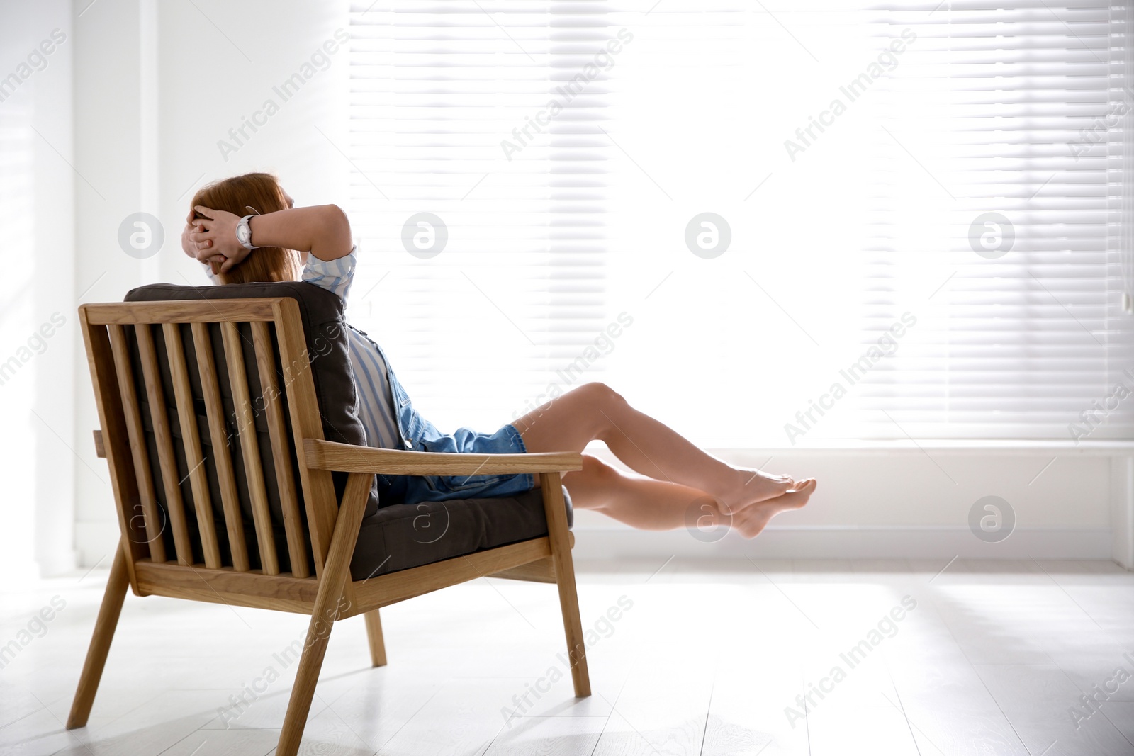 Photo of Young woman relaxing in armchair near window at home. Space for text