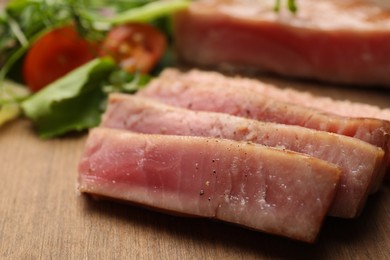 Photo of Pieces of delicious tuna steak on wooden board, closeup