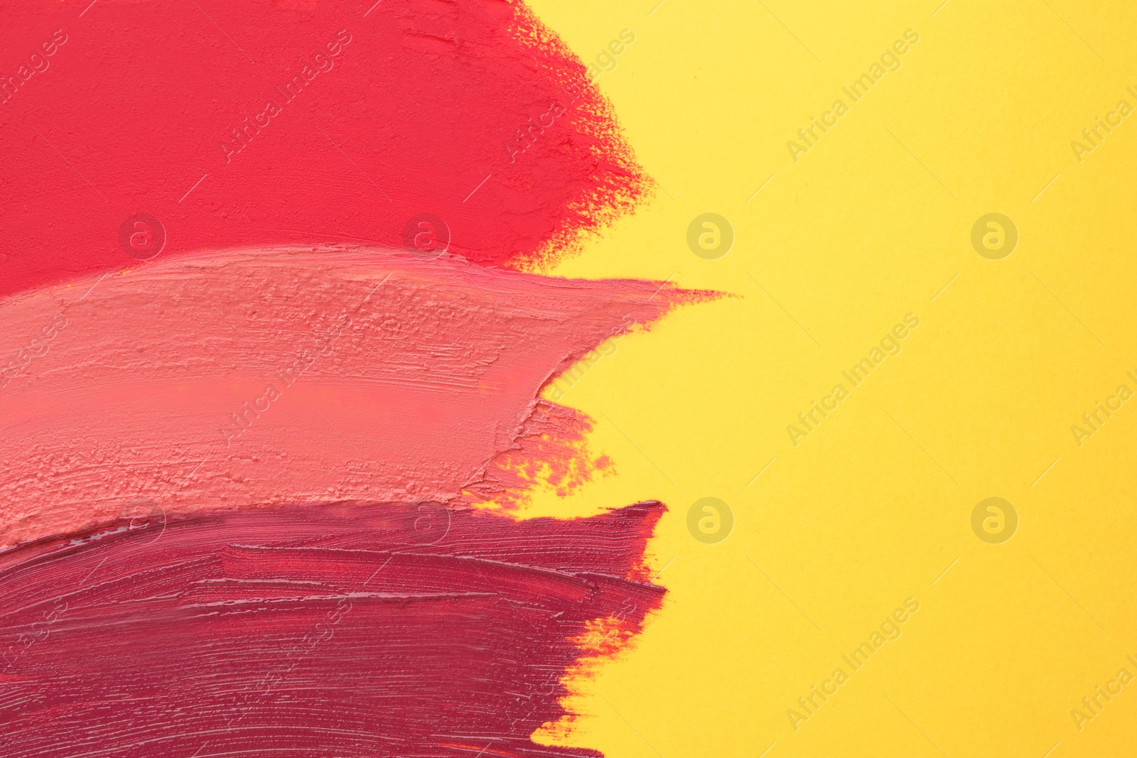 Photo of Smears of different beautiful lipsticks on yellow background, top view. Space for text