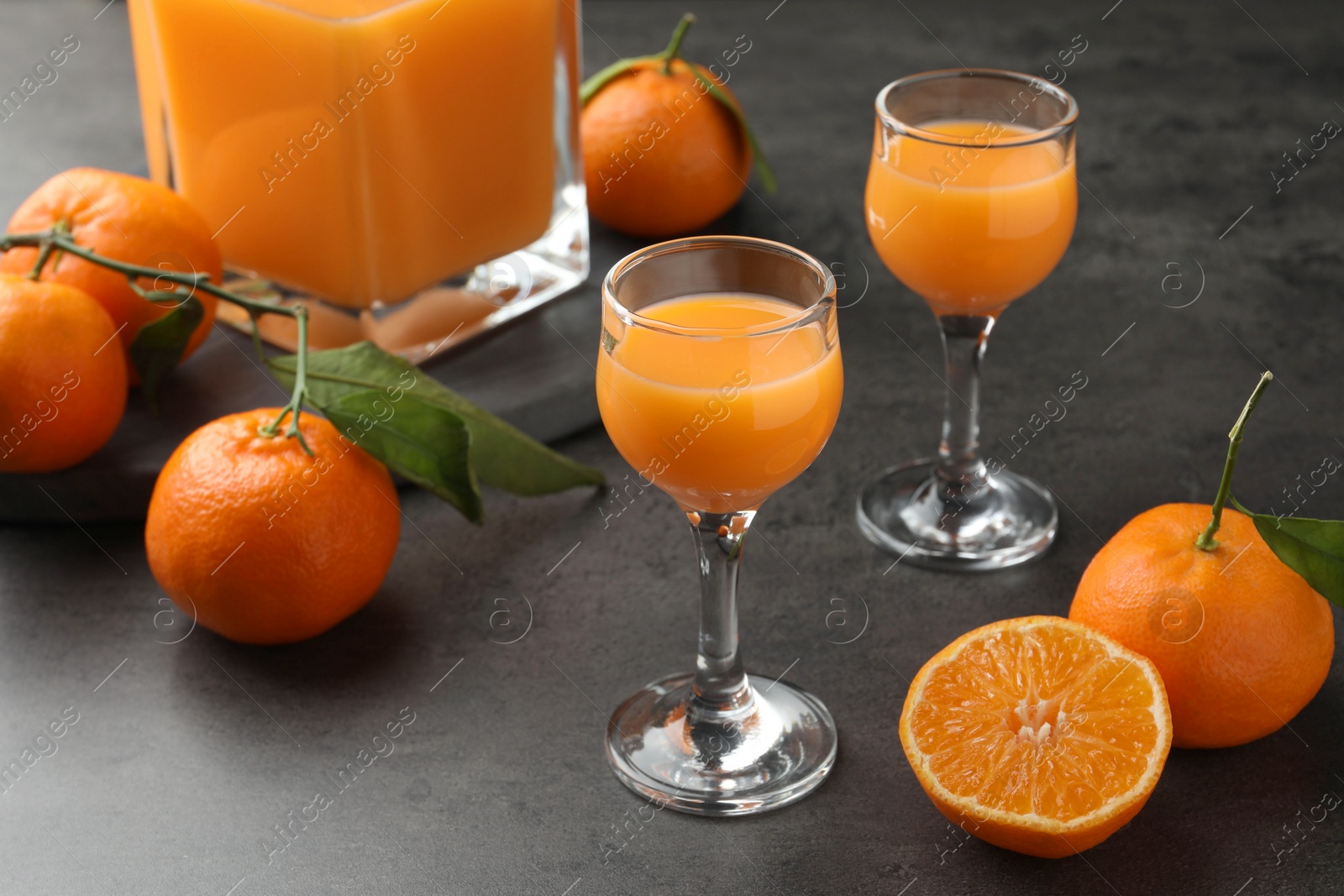 Photo of Delicious tangerine liqueur and fresh fruits on grey table