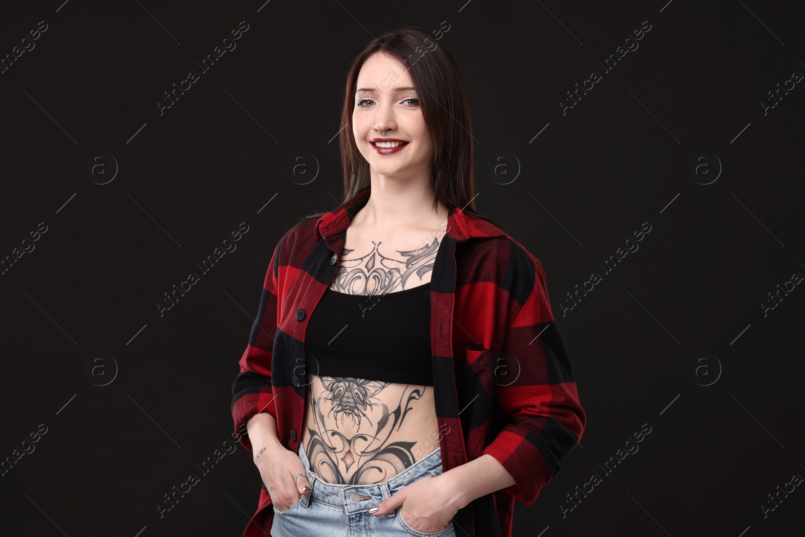 Photo of Portrait of smiling tattooed woman on black background